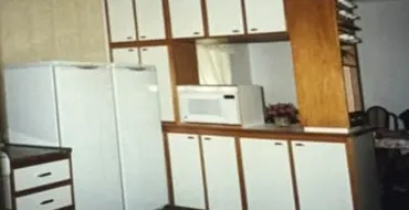 Fotografia antiga em papel: cozinha com armários brancos e madeira