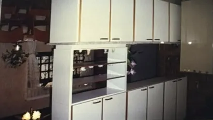 Fotografia antiga em papel: cozinha com armários brancos suspensos
