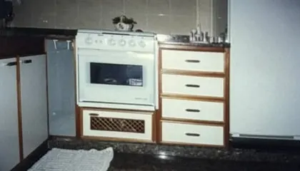 Fotografia antiga em papel: cozinha com gaveteiro branco e fogão embutido