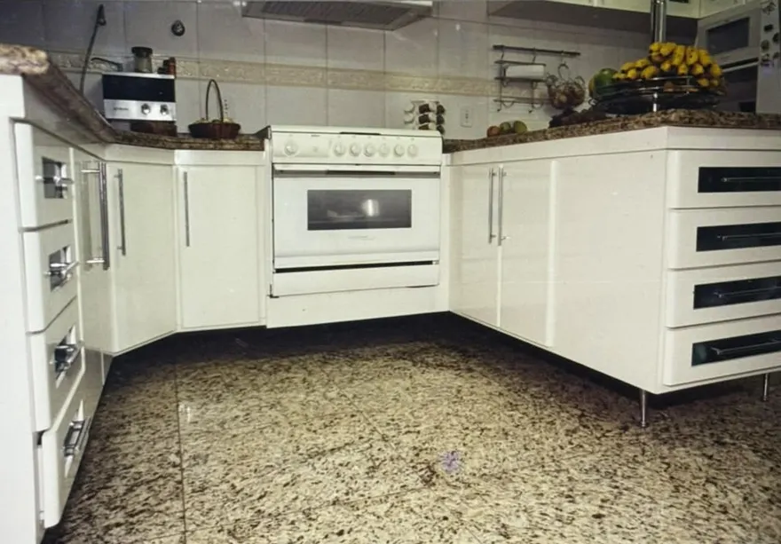 Fotografia antiga em papel: cozinha com armários brancos e bancada de granito