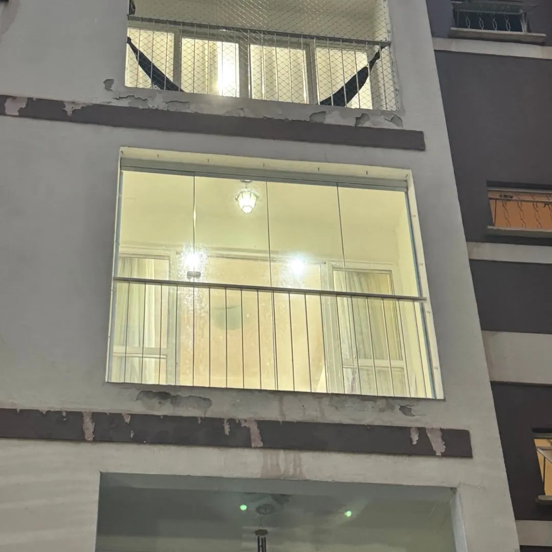 Sacada de apartamento envidraçada, iluminada por dentro, à noite