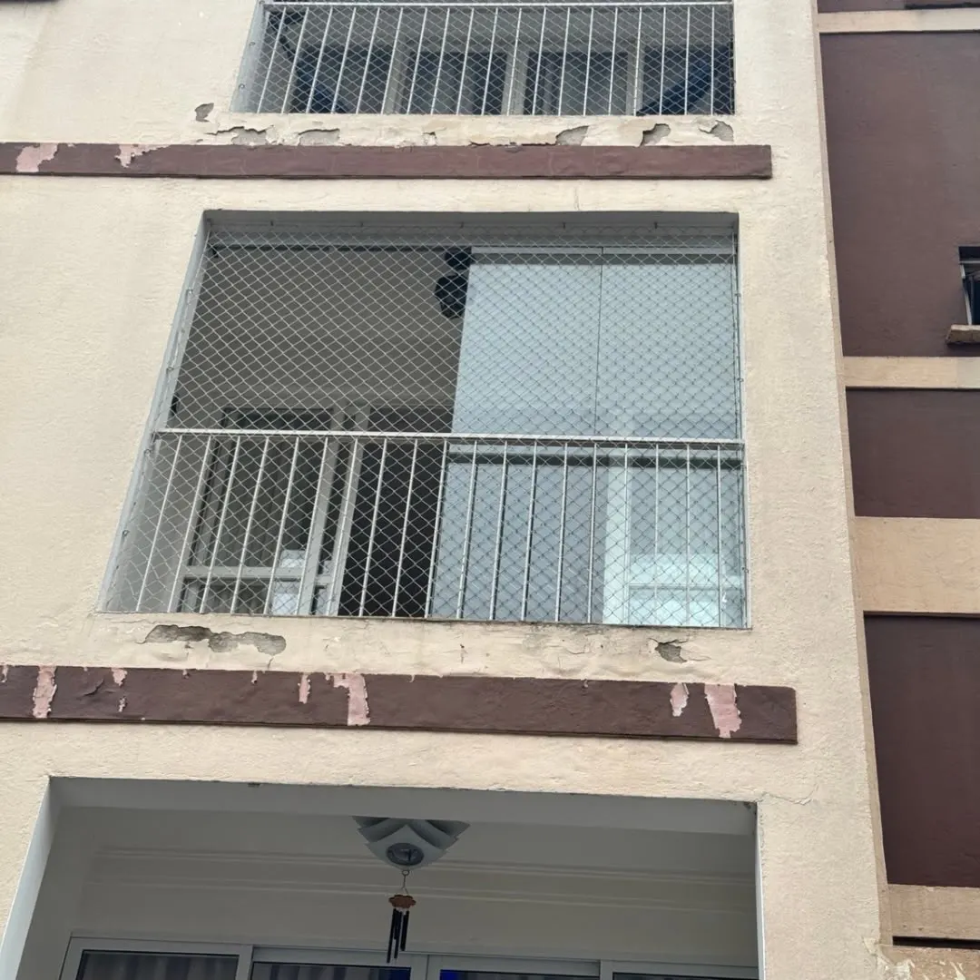Sacada de apartamento com rede de proteção, antes do fechamento em vidro