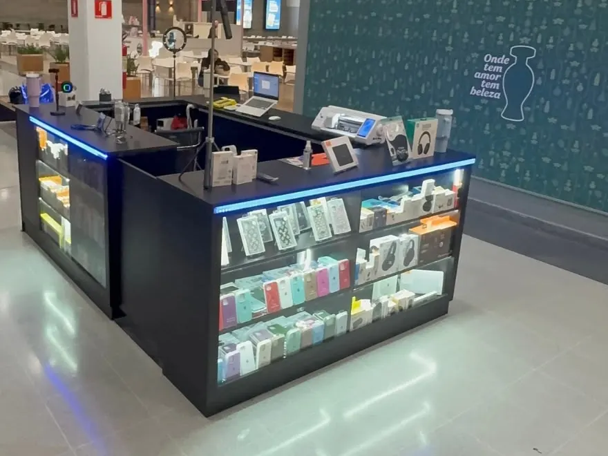 Quiosque de shopping em preto, com vitrines iluminadas e balcão de atendimento
