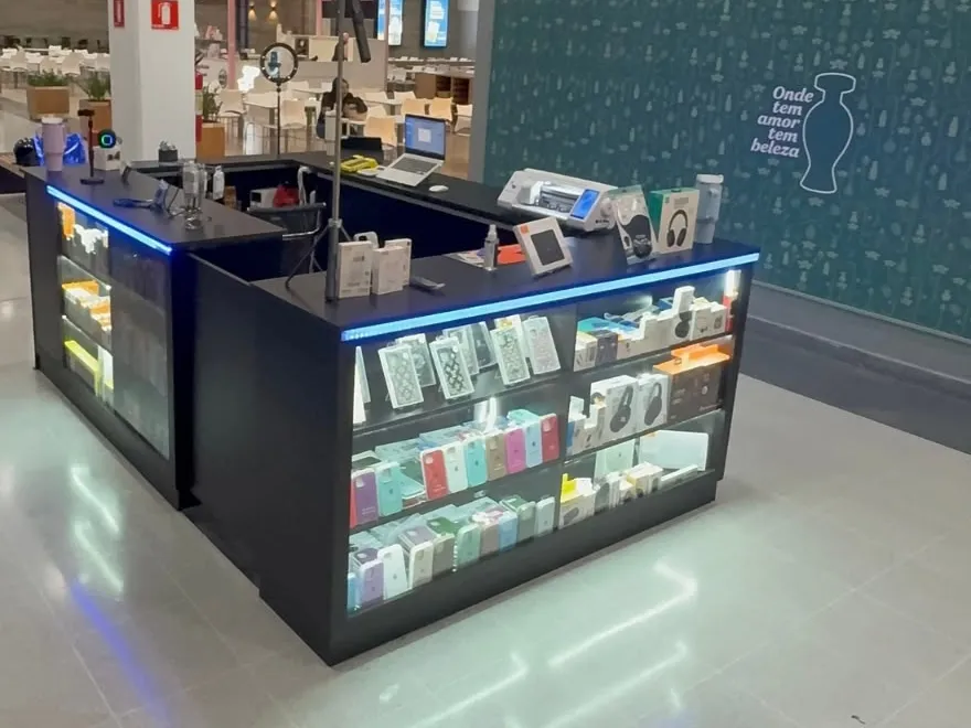 Quiosque de shopping em preto, com vitrines iluminadas e balcão de atendimento