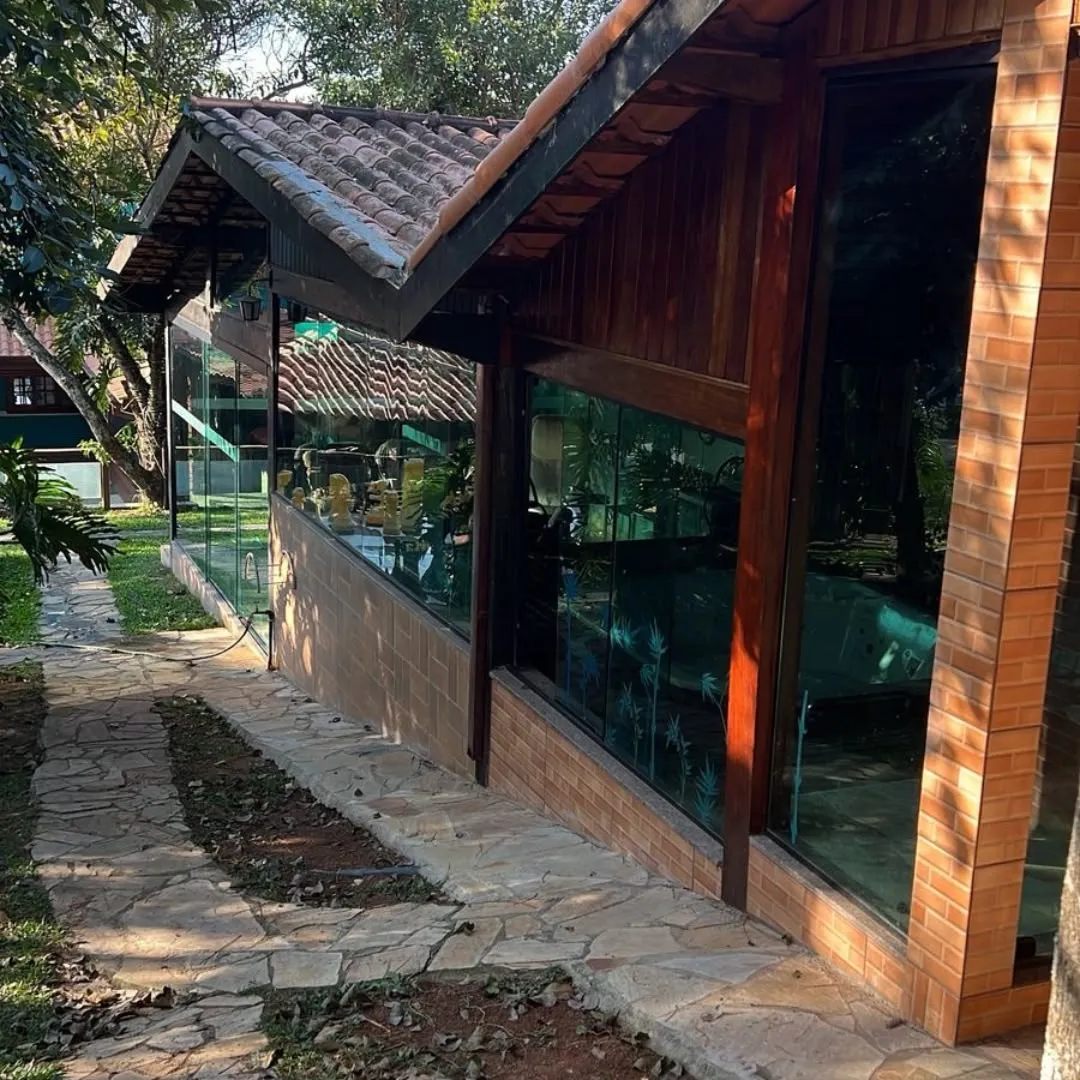 Varanda de casa de tijolo e madeira fechada com painéis de vidro