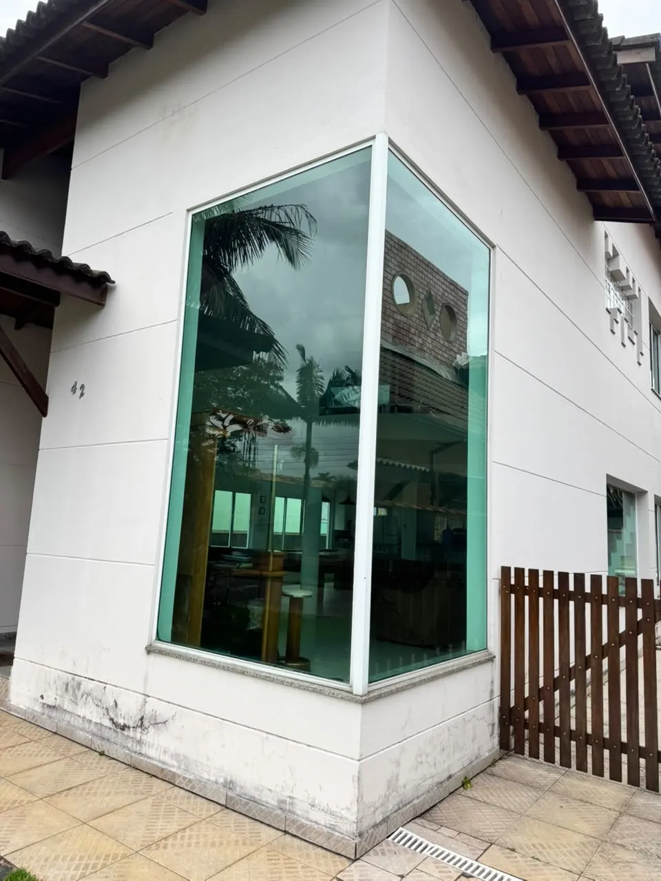 Janela de canto em vidro verde, do piso ao teto, em fachada branca