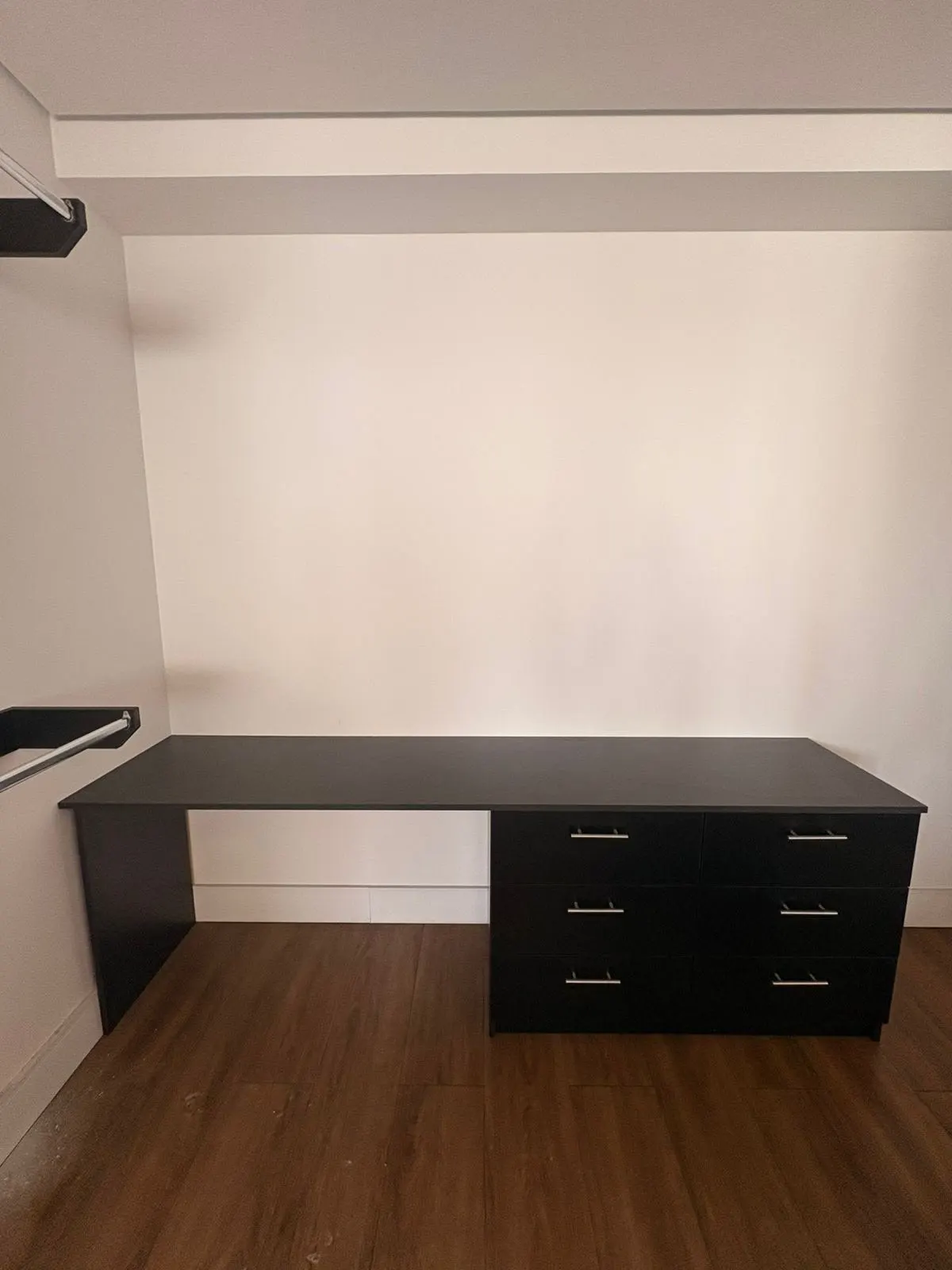 Mesa preta com gaveteiro em ambiente de piso de madeira