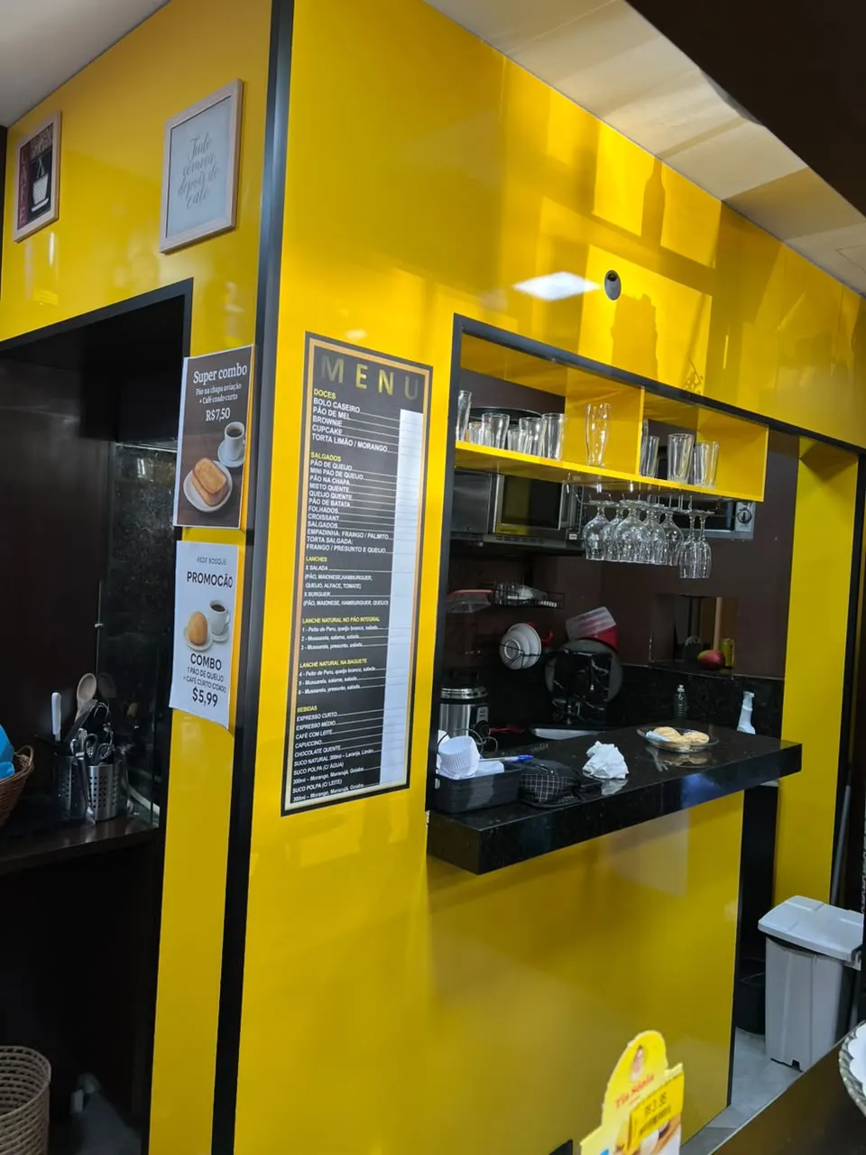 Balcão de atendimento de cafeteria com painéis amarelos e tampo preto