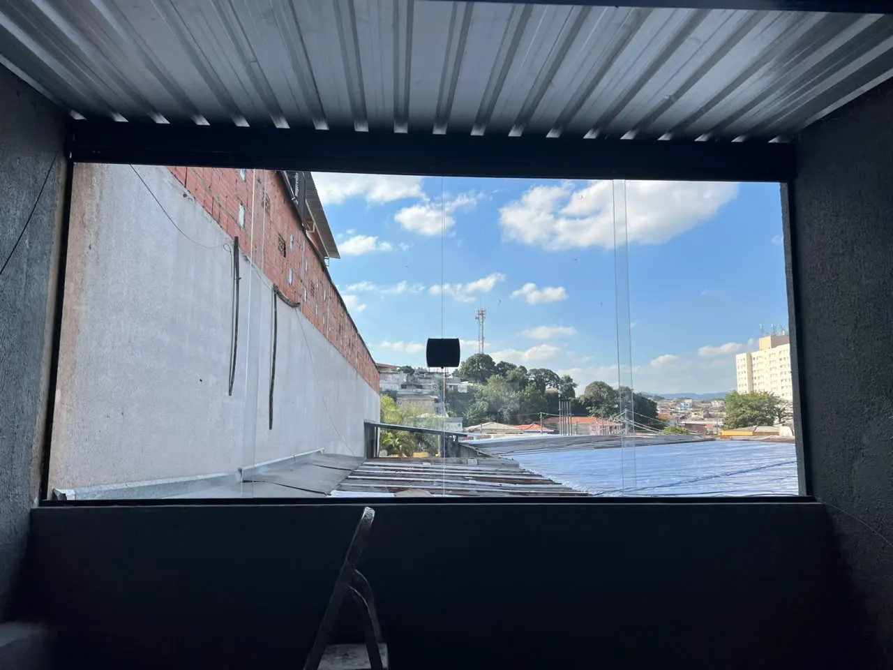 Vão largo fechado em vidro, visto de dentro, com a cidade ao fundo