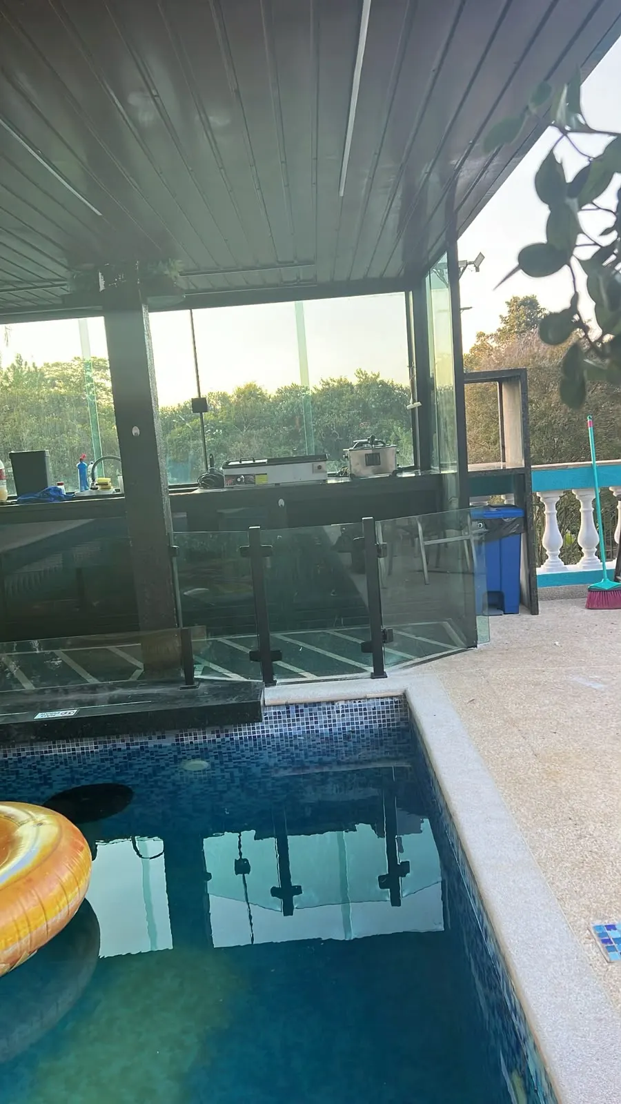 Área de piscina sob deck, com guarda-corpo e fechamento em vidro