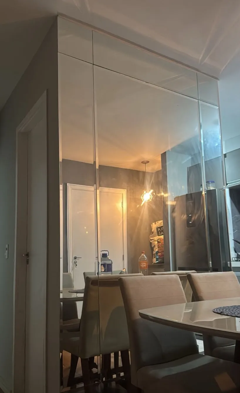 Parede revestida de espelho, do piso ao teto, em sala de jantar