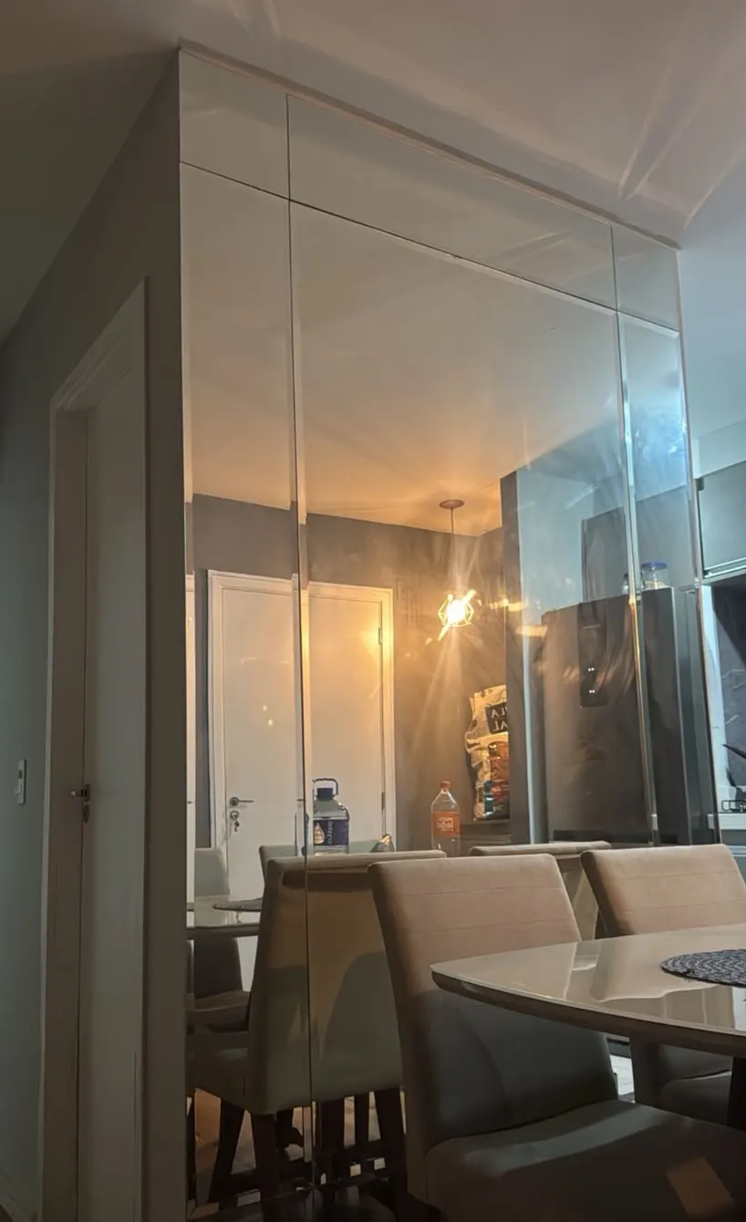 Parede revestida de espelho, do piso ao teto, em sala de jantar