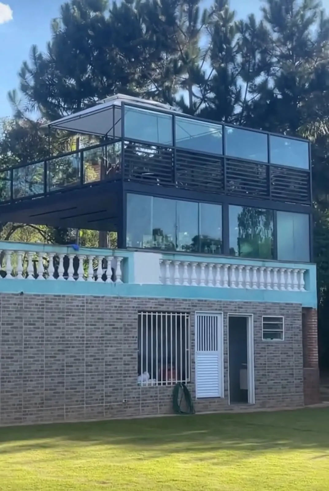 Deck elevado com fechamento e guarda-corpo em vidro, entre árvores