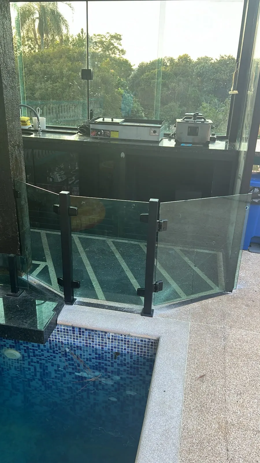 Guarda-corpo de vidro com colunas pretas na borda de uma piscina