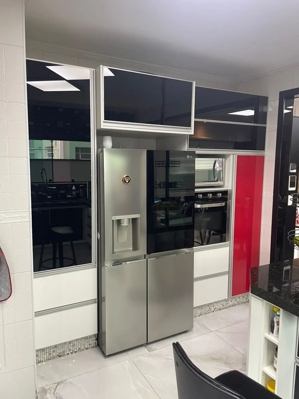Cozinha com portas de vidro preto, armários brancos e detalhe vermelho
